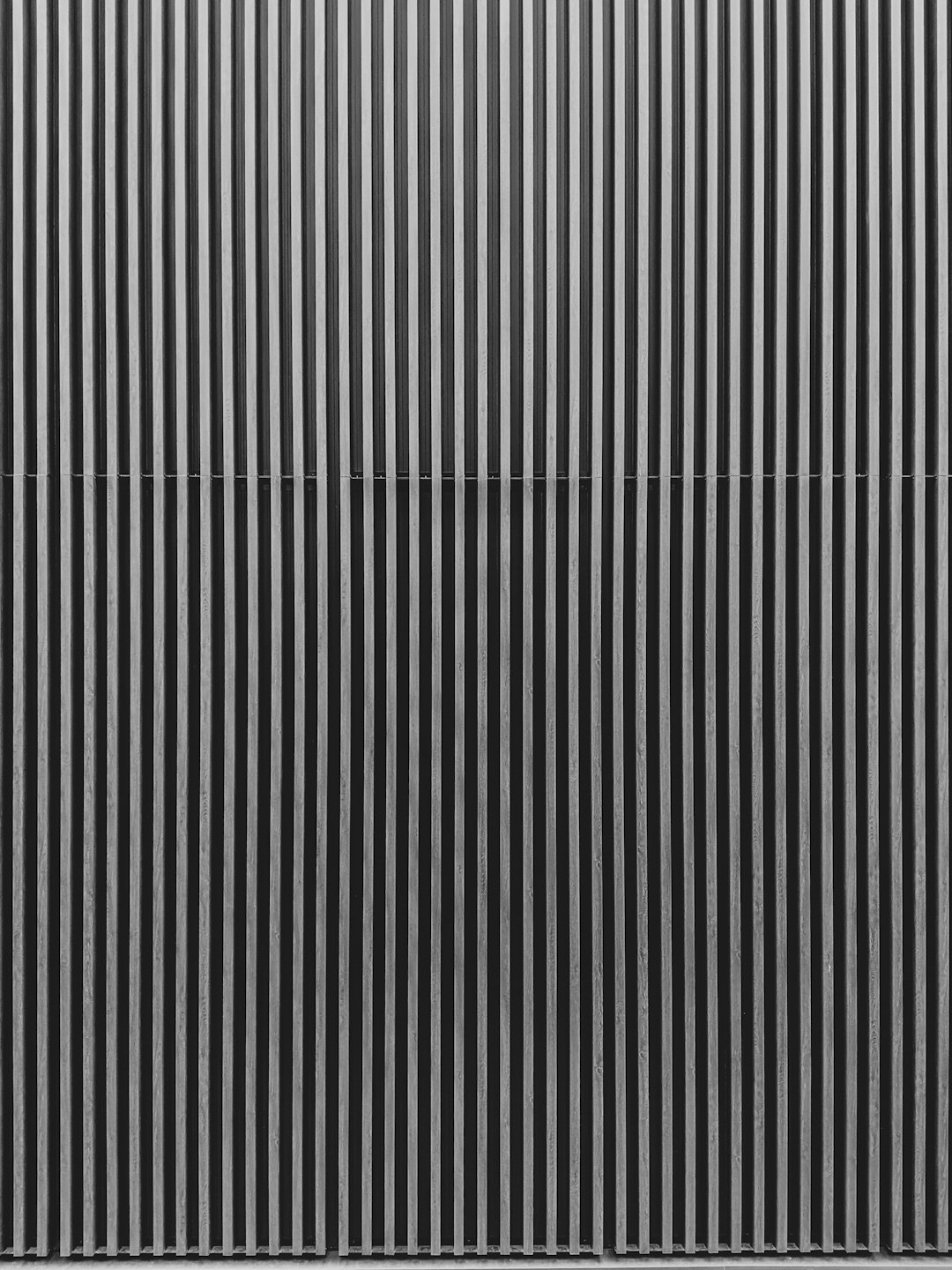 Modern wall constructed from vertical grey and white slats.