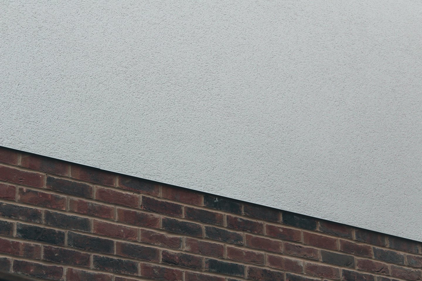 Building exterior with grey render and reddish-brown brickwork.