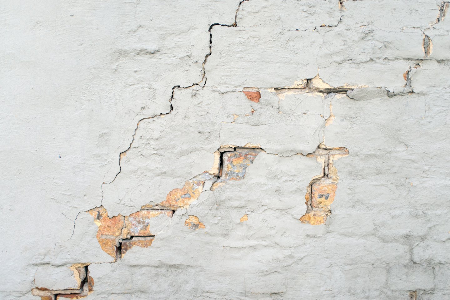 Cracked plaster walls reveal red bricks underneath the surface.